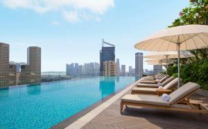 新加坡Andaz Singapore A Concept by Hyatt的大楼内带躺椅和遮阳伞的游泳池