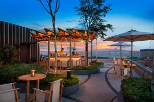 新加坡Andaz Singapore A Concept by Hyatt的屋顶餐厅设有桌子和遮阳伞