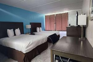金斯兰Travelodge by Wyndham Kingsland GA的酒店客房设有两张床和一张桌子。