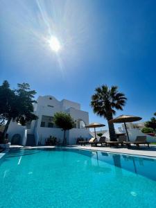 梅萨雷亚Santorini Garden Homes的一个带椅子和遮阳伞的大型游泳池