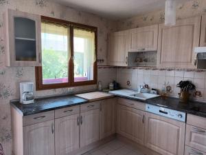 Boissey-le-ChâtelGite maison de campagne的厨房配有木制橱柜、窗户和水槽。