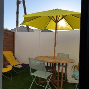 拉罗谢尔Guest House entre ville et océan的一张桌子和椅子,配有黄色雨伞