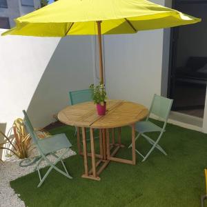 拉罗谢尔Guest House entre ville et océan的一张桌子和椅子,配有黄色雨伞