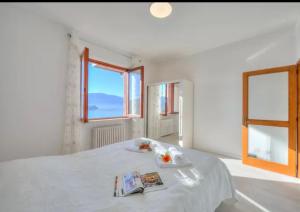 拉韦诺Apartment With View Lake Maggiore/Laveno Mombello的一间白色的卧室,配有一张带杂志的床