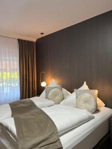比斯平根Hotel Harmshof Bispingen的卧室配有一张带白色床单和枕头的大床。