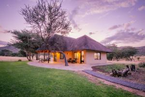 温特和克Okapuka Safari Lodge的田野上茅草屋顶的小房子