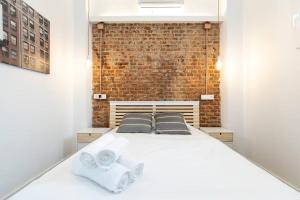 马德里Apartamento 1hab con estilo cerca de Ventas的卧室配有白色的床和砖墙