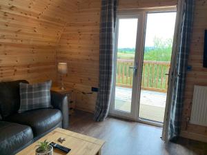 KeltyPond View Pod 3 With Private Hot Tub - Pet Friendly -Fife - Loch Leven - Lomond Hills的带沙发的客厅和阳台