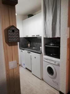 ChaillolStudio RDC 4-5 pers pied des pistes的厨房配有白色橱柜和洗衣机。