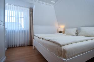 韦斯特兰Villa am Meer的白色的卧室设有床和窗户