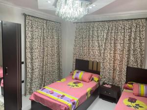 Kafr Abū ʼumaydahشقة فندقية 3 غرف كمبوند الخمائل的一间卧室配有粉红色的床和吊灯。