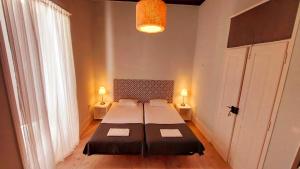法鲁Hostel A Casa da Árvore的一间卧室配有一张床、两盏灯和一个窗户。