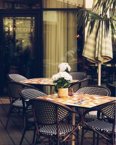 布洛涅-比扬古Le Parchamp, a Tribute Portfolio Hotel, Paris Boulogne的桌子上摆放着椅子,花瓶上放着花