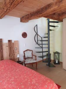 LajouxAu Château的一间卧室设有红色的床和螺旋楼梯。