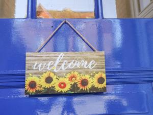 斯卡伯勒Lonsdale Villa的蓝色门上的欢迎标志,带向日葵