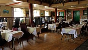 巴里格曼海景小酒馆酒店的餐厅配有桌椅和白色桌布