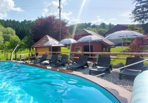 Šmarje pri JelšahGREEN LAND Family Fun Sport Resort的一个带椅子和遮阳伞的游泳池以及一座房子