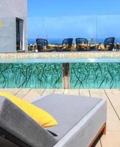 大加那利岛拉斯帕尔马斯Design Plus Bex Hotel的水边带椅子和床的游泳池