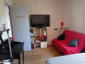 屈埃尔西地区古尔东studio type 1bis的客厅配有红色沙发和平面电视