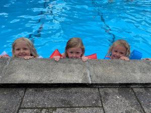 StoubyLøgballe Camping & Cottages的三名儿童在游泳池边看