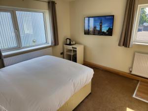 伦敦Homefield Lodge的卧室配有一张床,墙上配有电视。