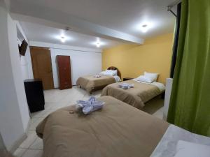 库斯科Tayta Wasi Hotel的酒店客房带两张床,上面有弓