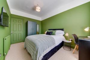 利物浦Air Host and Stay - Rockfield Lodge, sleep 12 free parking next to LFC的一间卧室设有绿色的墙壁、一张床和一张桌子