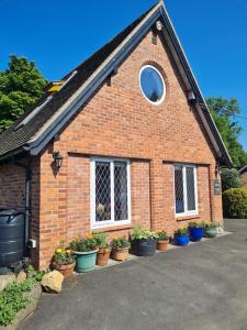 BroomeTopsy-Turvy, Gardeners Cottage, Clungunford, Ludlow, Shropshire SY70PN的前面有盆栽植物的砖房