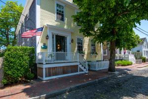 楠塔基特Nantucket Periwinkle的前廊上悬挂着美国国旗的黄色房子