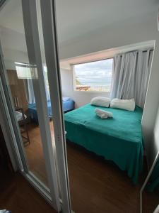 莫罗圣保罗Casa de Praia的一间卧室设有一张绿色的床和一个窗户。