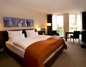 不莱梅不来梅大西洋大酒店的酒店客房设有一张大床和一张书桌。