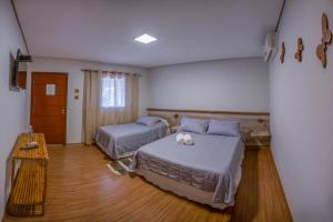 沙帕达-杜斯吉马朗伊斯Pousada Vento Sul的一间卧室设有两张床,铺有木地板