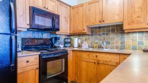 太阳峰Settlers Crossing #61 by Bear Country的厨房配有木制橱柜和黑炉灶烤箱。