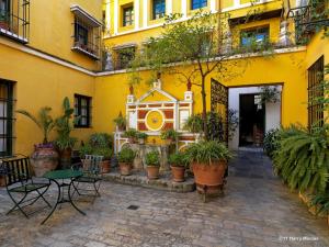 塞维利亚犹太人之家酒店的庭院里黄色的建筑,有桌子和盆栽植物