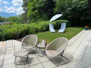 阿特湖畔翁特拉赫Die Landhausvilla in Unterach am Attersee的庭院里设有两把椅子和一张桌子及一把遮阳伞