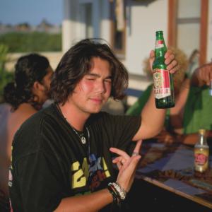 勒吉安Sunshot Hostel的一位年轻人拿着一瓶啤酒