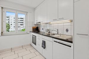 温特图尔Spacious-Excellent Connection-Parking-Washer的厨房配有白色橱柜、水槽和窗户。