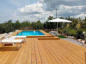 马丁纳弗兰卡Trullo Vito in Valle D itria con piscina的木甲板设有游泳池和遮阳伞