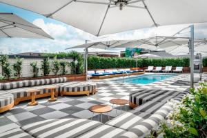 萨凡纳Perry Lane Hotel, a Luxury Collection Hotel, Savannah的一个带遮阳伞和椅子的游泳池和一个庭院