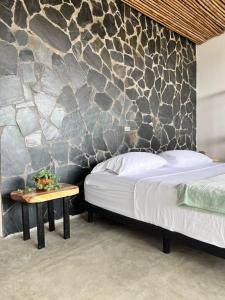 PapagallerosNatural Luxury Hotel的一间卧室设有一张床和石墙