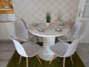 帕拉钦Apartman Marija的一张带四把椅子的白色桌子和一株植物
