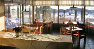 阿克博格洪堡德-豪斯酒店的餐厅设有桌椅和大窗户。