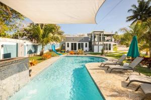 下维加Ocean Front Villa, 2 Private Pools, BBQ, Tennis court and more!的一个带椅子的游泳池以及一座房子
