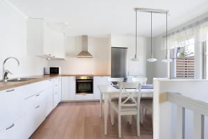 博登Guestly Homes - 4BR Villa, 6 Beds with 2 Showers的厨房配有白色橱柜和桌椅