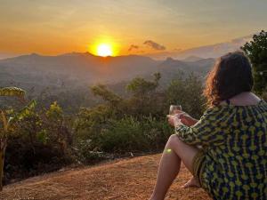 La LagunaHawk's Nest Bed & Breakfast的坐在山坡上拍摄日落景象的女人
