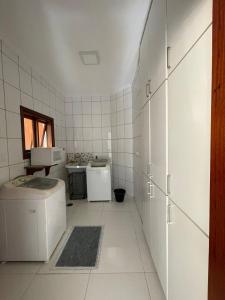 圣若泽杜斯坎普斯Casa Jardim das Colinas的白色瓷砖厨房配有洗衣机和烘干机