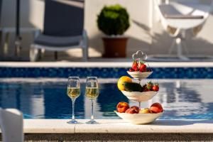 苏托莫雷Delfin Apartments的游泳池旁的水果和酒杯托盘
