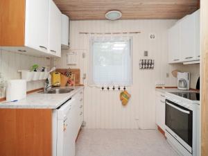 伊斯科博约格6 person holiday home in Eskebjerg的厨房配有白色橱柜、水槽和窗户。