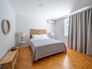 PetritíVilla Kostamaria的一间铺有木地板的白色卧室,配有一张床