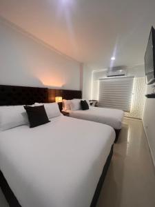 卡塔赫纳Hotel Zuriel Boutique的配有电视的酒店客房内的两张大床